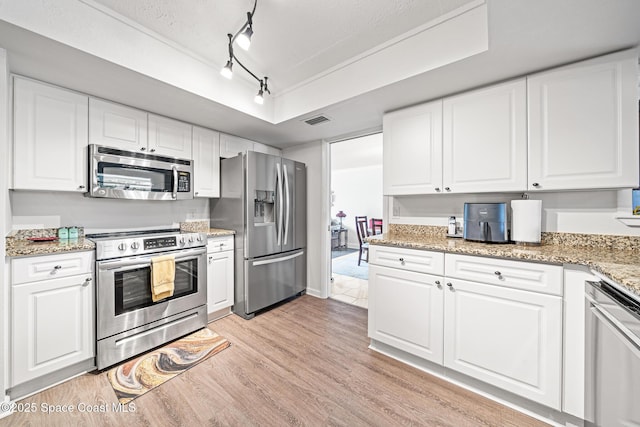 445 Park Ave, Satellite Beach, FL 32937 - kitchen featuring appliances with stainless steel finishes, light wood-type flooring, white cabinets, and light stone counters