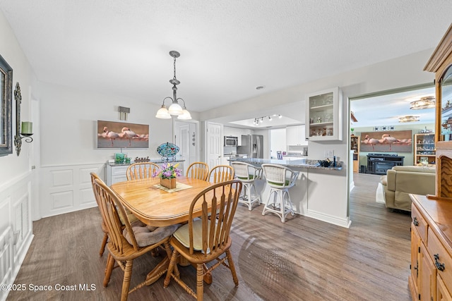 445 Park Ave, Satellite Beach, FL 32937 - dining area featuring wood finished floors, a chandelier, a fireplace, and a textured ceiling