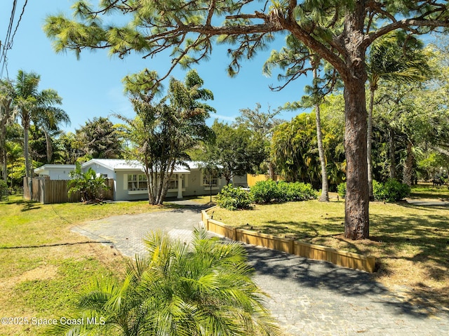 view of yard featuring decorative driveway and fence