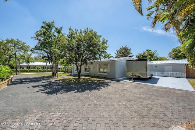 view of front of home with decorative driveway, fence, and stucco siding