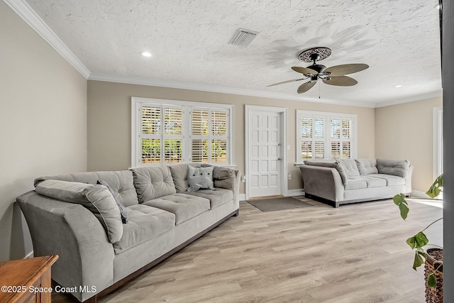 living room with visible vents, light wood finished floors, a ceiling fan, and crown molding