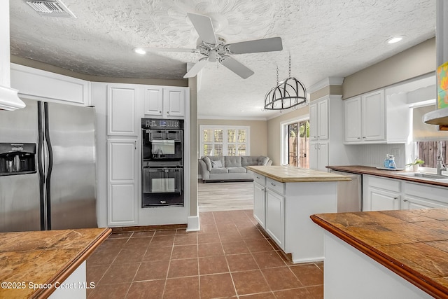 kitchen with a ceiling fan, visible vents, stainless steel fridge with ice dispenser, butcher block countertops, and dobule oven black
