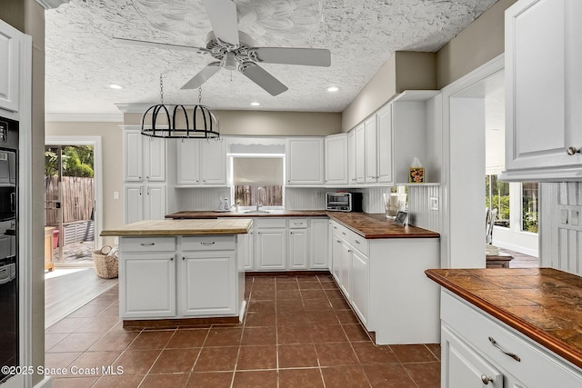kitchen with dark tile patterned flooring, a textured ceiling, white cabinetry, butcher block counters, and ceiling fan