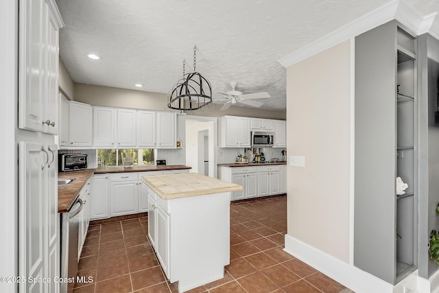 kitchen featuring stainless steel appliances, dark tile patterned flooring, a center island, and a ceiling fan