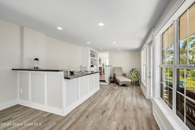 interior space with recessed lighting, built in shelves, a textured ceiling, and light wood-style floors