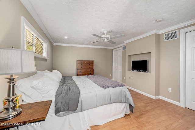 bedroom featuring a textured ceiling, visible vents, light wood finished floors, and ornamental molding