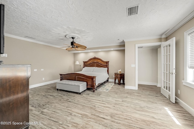 bedroom with visible vents, baseboards, ornamental molding, and light wood finished floors