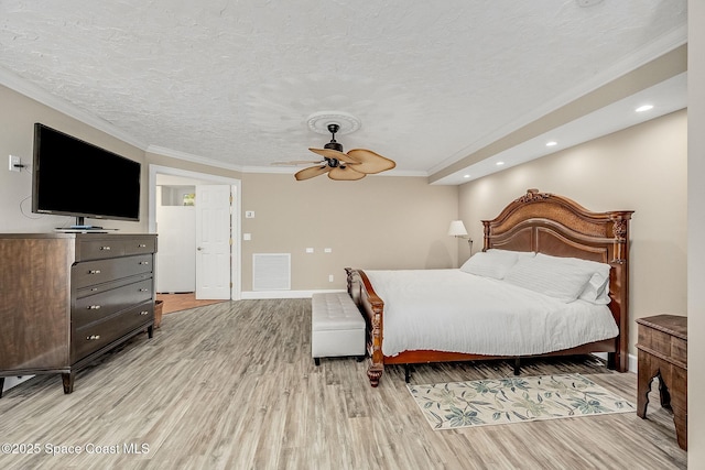 bedroom with a textured ceiling, visible vents, light wood-type flooring, and ornamental molding