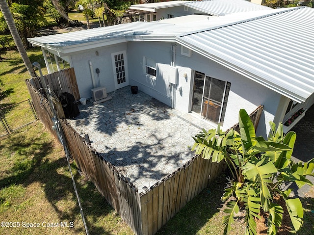 exterior space with stucco siding, metal roof, a patio, and fence