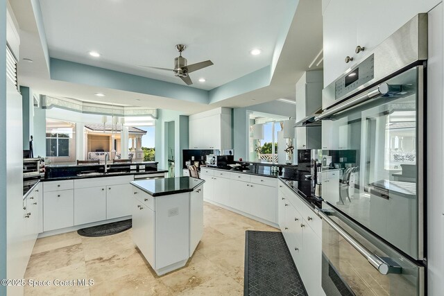 601 N Swim Club Dr Pha, Pha, Indian River Shores, FL 32963 - kitchen featuring a tray ceiling, a kitchen island, a sink, dark countertops, and ceiling fan