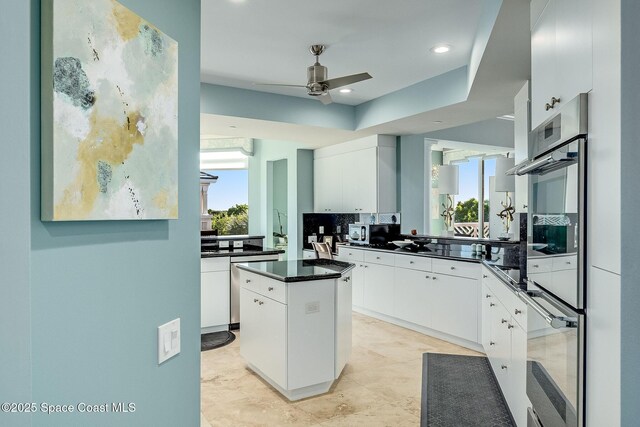 601 N Swim Club Dr Pha, Pha, Indian River Shores, FL 32963 - kitchen with white cabinetry, oven, a kitchen island, dark countertops, and a ceiling fan