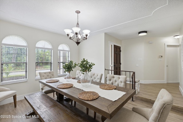 dining room featuring a textured ceiling, an inviting chandelier, and light wood-style floors