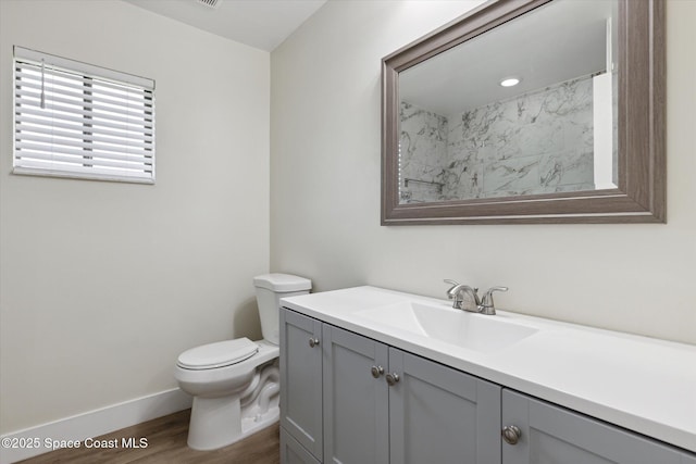 bathroom with baseboards, wood finished floors, toilet, and vanity