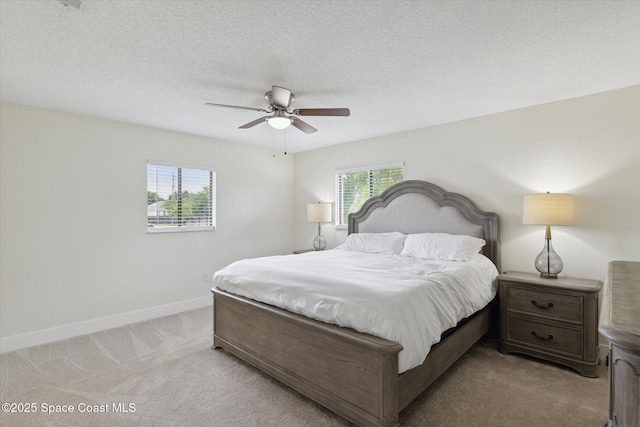 bedroom featuring light carpet, multiple windows, baseboards, and a textured ceiling