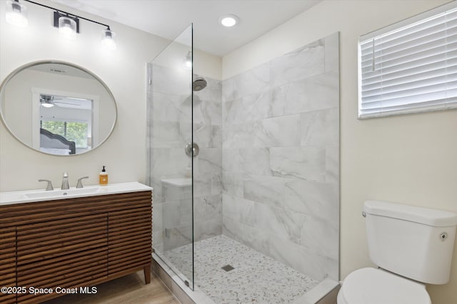full bathroom with walk in shower, ceiling fan, toilet, wood finished floors, and vanity