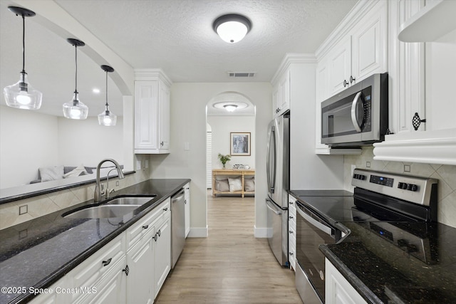 kitchen with visible vents, white cabinetry, a sink, and stainless steel appliances