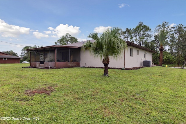 rear view of property with central AC unit, stucco siding, a sunroom, and a yard