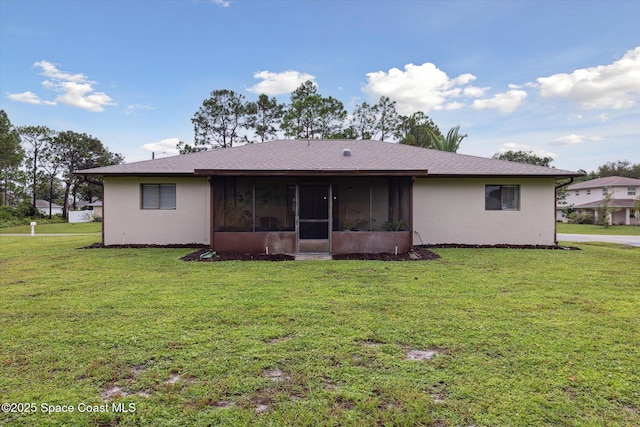 back of property with a sunroom, stucco siding, and a lawn