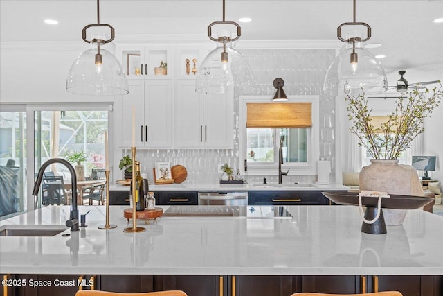kitchen with hanging light fixtures, ornamental molding, a sink, and dishwasher
