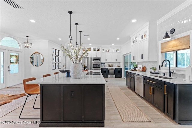 kitchen featuring crown molding, a sink, a breakfast bar, stainless steel appliances, and visible vents