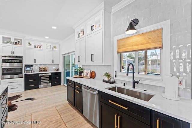 kitchen featuring white cabinetry, a sink, beverage cooler, appliances with stainless steel finishes, and dark cabinets