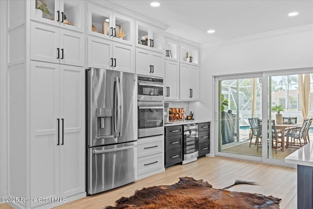 kitchen with light countertops, white cabinetry, beverage cooler, stainless steel appliances, and ornamental molding