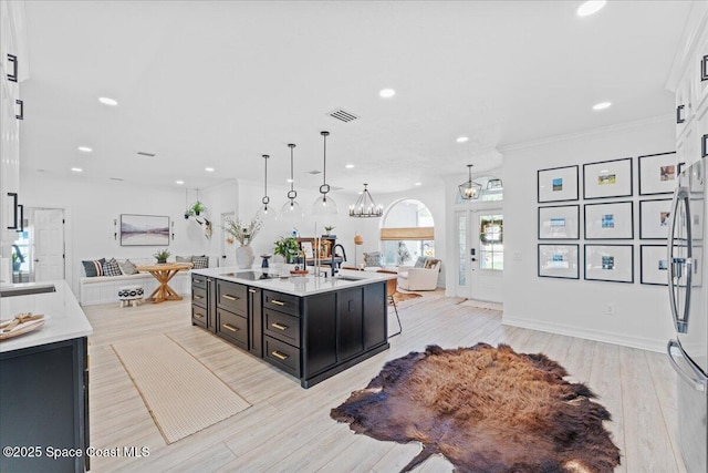 kitchen featuring light countertops, a sink, dark cabinetry, open floor plan, and visible vents