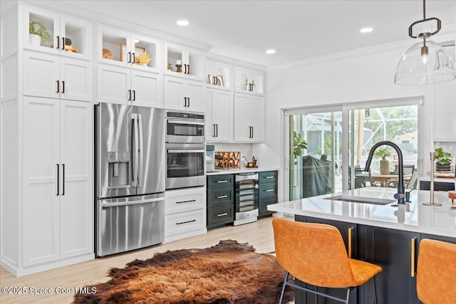 kitchen featuring a sink, beverage cooler, stainless steel appliances, white cabinets, and ornamental molding