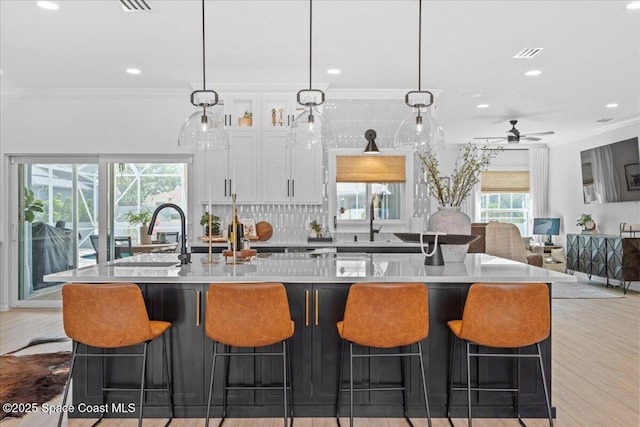 kitchen featuring white cabinets, crown molding, light wood-style floors, and visible vents