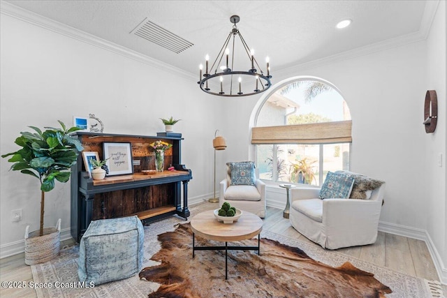 living area with visible vents, an inviting chandelier, crown molding, and wood finished floors