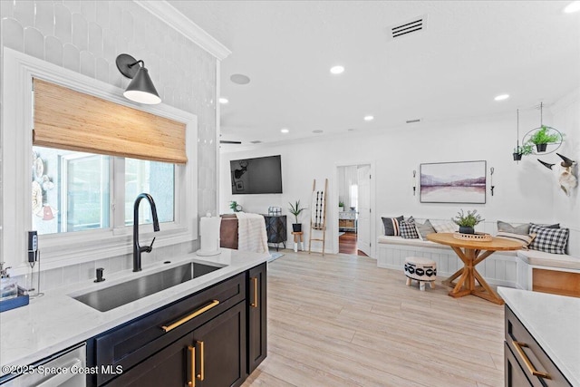 kitchen with crown molding, a sink, dishwasher, open floor plan, and visible vents