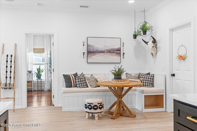 interior space with visible vents, crown molding, light wood-style floors, and breakfast area