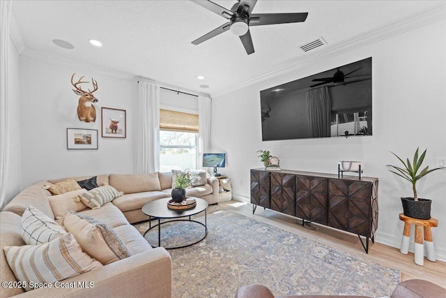living area with a ceiling fan, wood finished floors, baseboards, visible vents, and ornamental molding