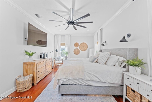 bedroom featuring visible vents, baseboards, ornamental molding, ceiling fan, and wood finished floors