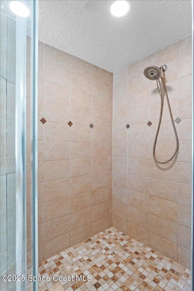 full bathroom with a tile shower and a textured ceiling