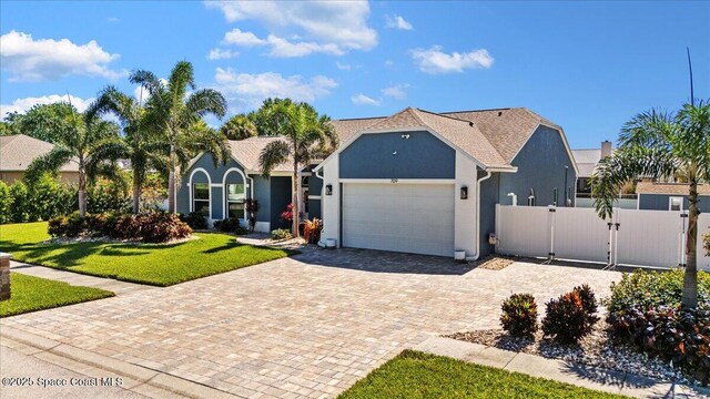 view of front of property featuring a front yard, a gate, fence, an attached garage, and decorative driveway