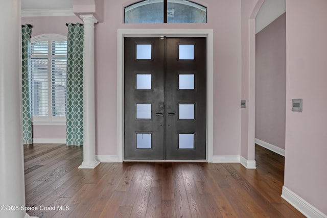 entryway with ornate columns, baseboards, ornamental molding, and wood finished floors