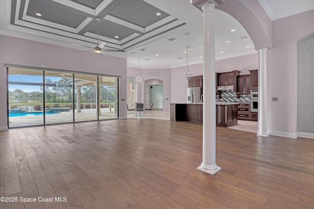 unfurnished living room featuring hardwood / wood-style floors, ornamental molding, a towering ceiling, and a ceiling fan