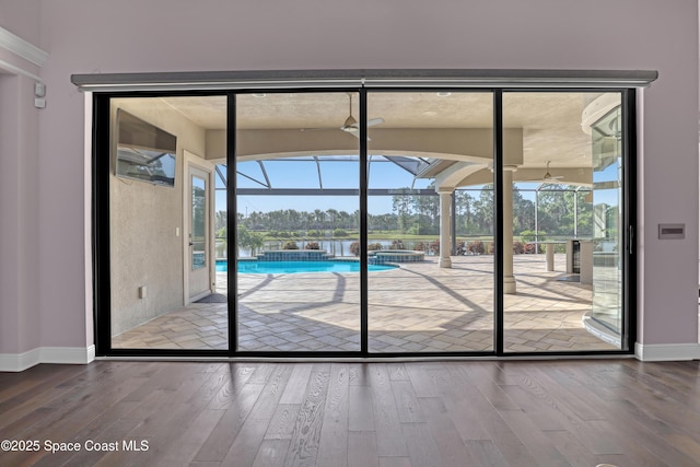 doorway featuring a sunroom, wood-type flooring, and baseboards