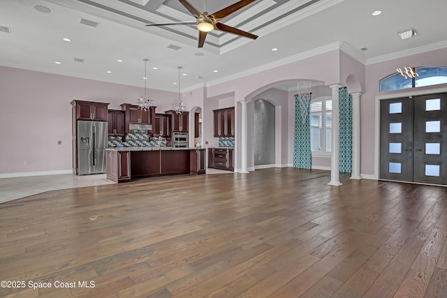 unfurnished living room featuring ornamental molding, ornate columns, arched walkways, and ceiling fan with notable chandelier