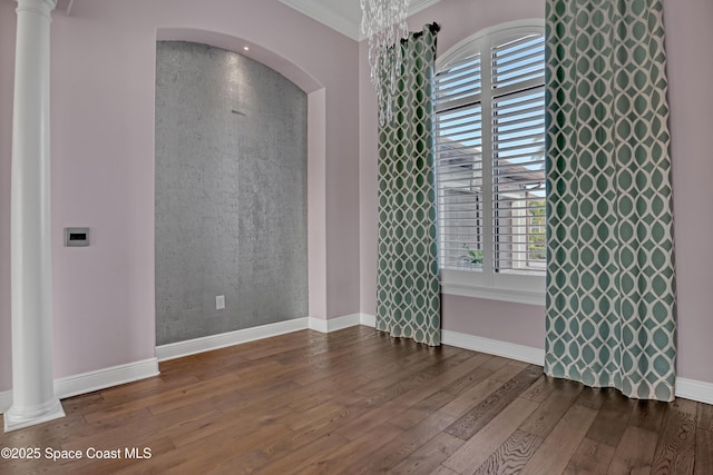 unfurnished room featuring arched walkways, wood-type flooring, and baseboards