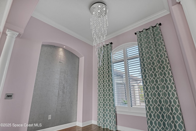 unfurnished room with baseboards, dark wood-style floors, crown molding, ornate columns, and arched walkways