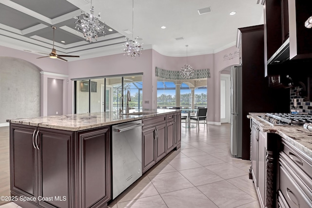 kitchen with arched walkways, a sink, a center island with sink, ceiling fan with notable chandelier, and stainless steel appliances