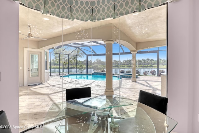 view of swimming pool featuring a water view, a pool with connected hot tub, outdoor dining space, a patio, and a lanai