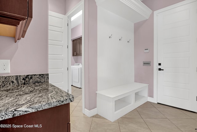 mudroom with light tile patterned floors, baseboards, and washing machine and dryer