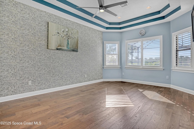 unfurnished room with a healthy amount of sunlight, ceiling fan, baseboards, and wood finished floors