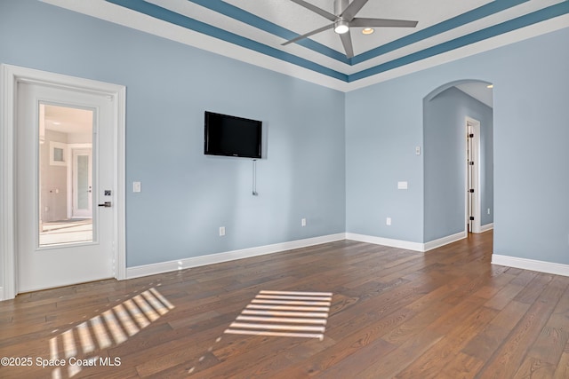 unfurnished living room featuring arched walkways, wood-type flooring, baseboards, and a ceiling fan