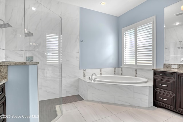 bathroom featuring tile patterned floors, a bath, a walk in shower, and vanity