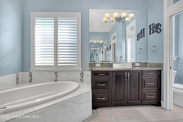 full bath with an inviting chandelier, toilet, vanity, tile patterned floors, and a garden tub