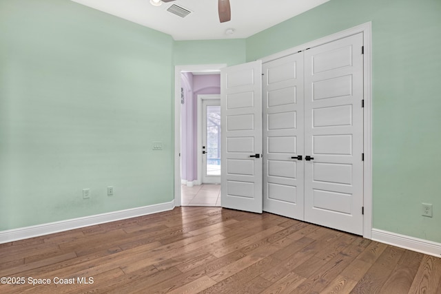 unfurnished bedroom with visible vents, baseboards, wood-type flooring, and a closet